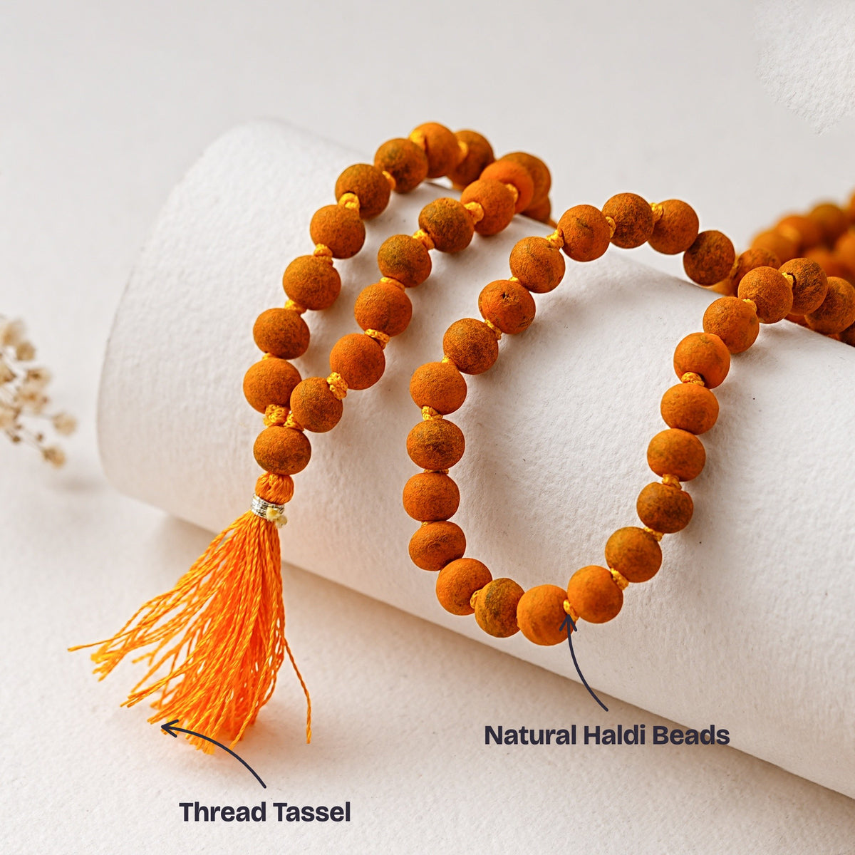 Close-up of the round natural Haldi beads and the orange thread tassel