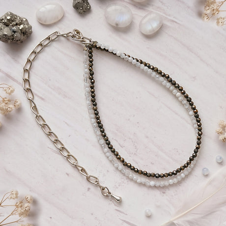 Pyrite and quartz anklet on white marble beside raw pyrite and polished stones