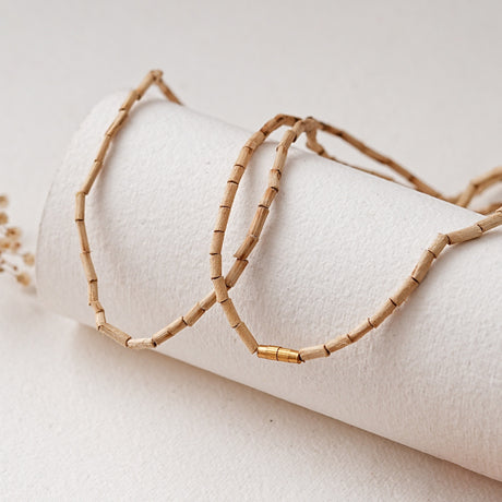Elongated-bead Tulsi Kanthi Mala draped over a roll of handmade paper