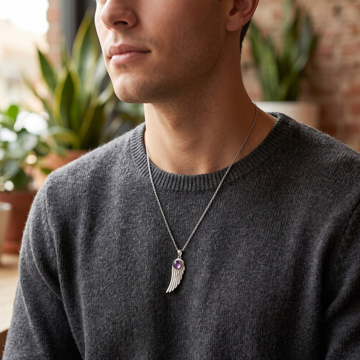 Man wearing the amethyst feather pendant over a grey sweater
